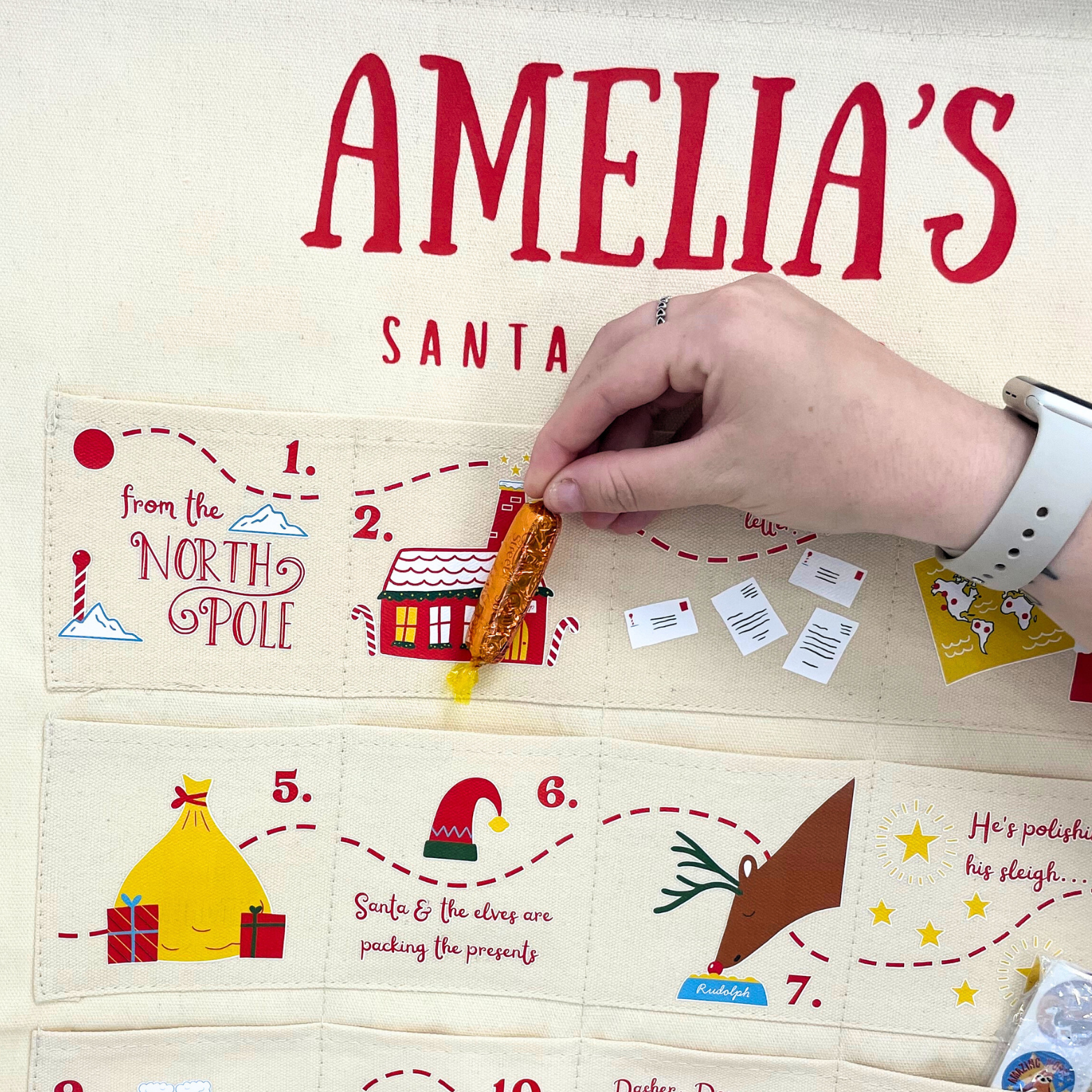 Child placing a small gift into one of the pockets of the Santa Tracker calendar.