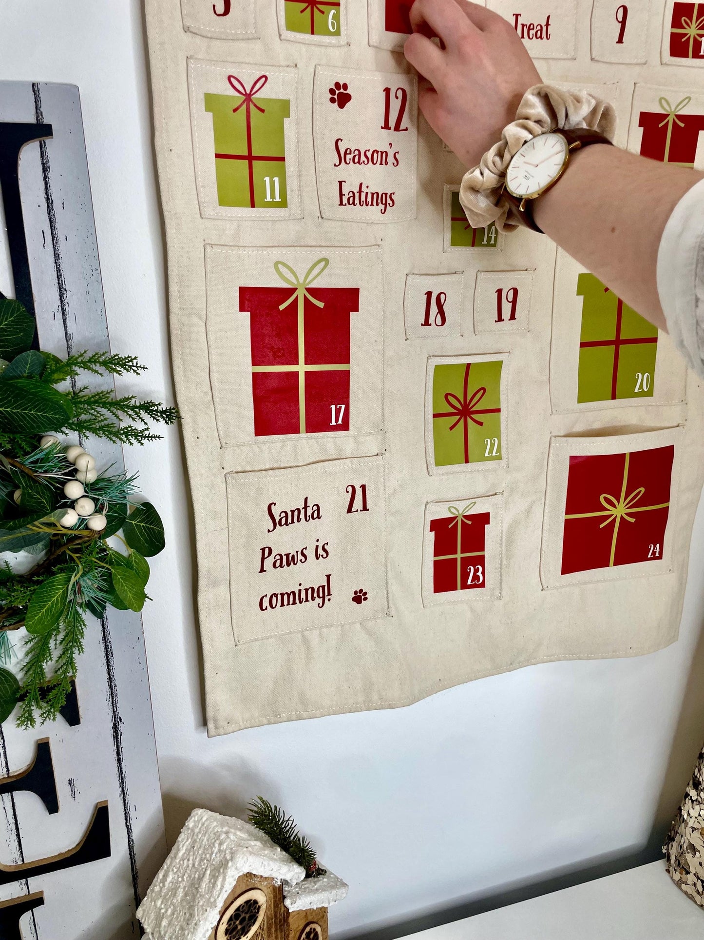 Cute pet advent calendar hanging on wall with treats in numbered pockets