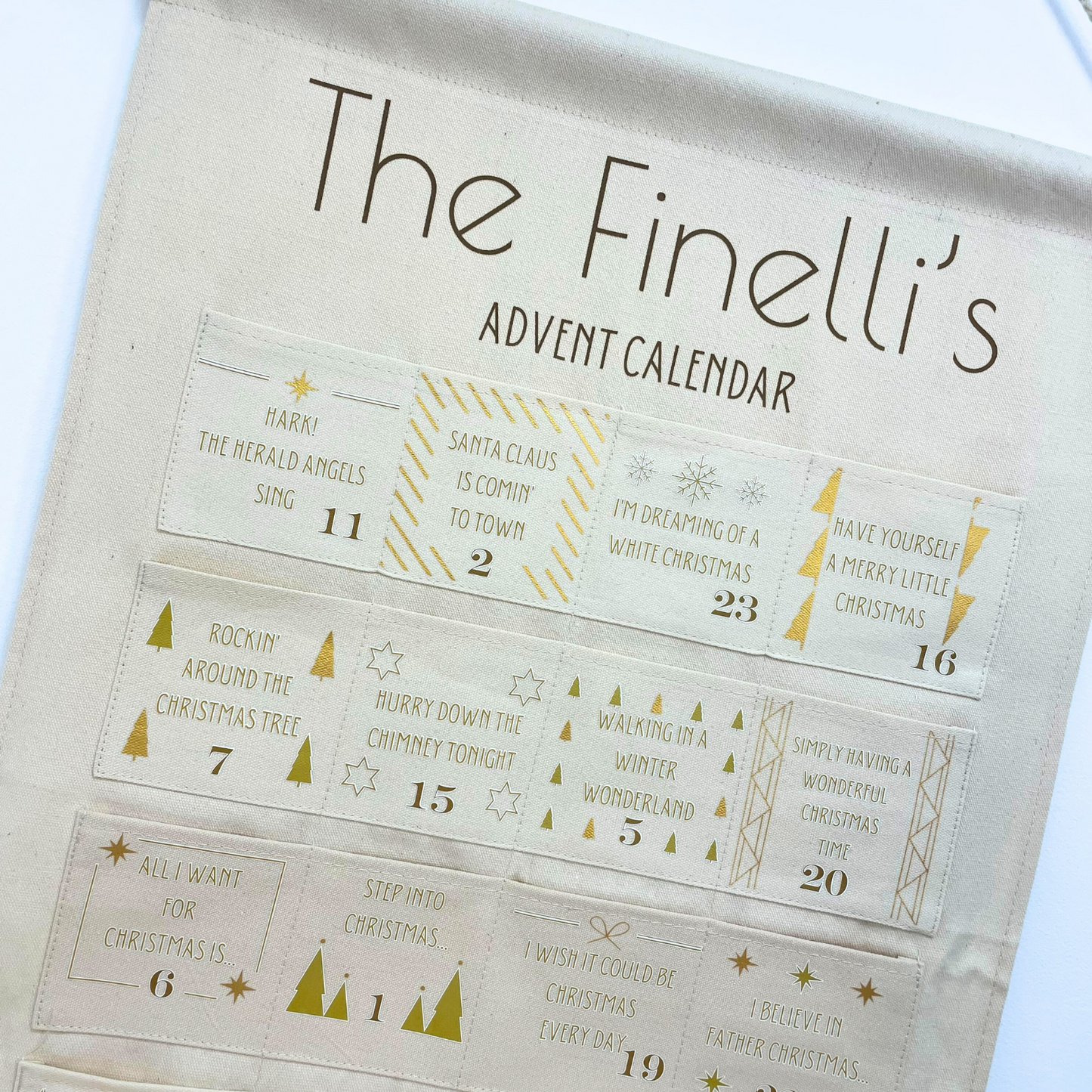 Personalised festive song calendar hanging on wall with 24 numbered pockets