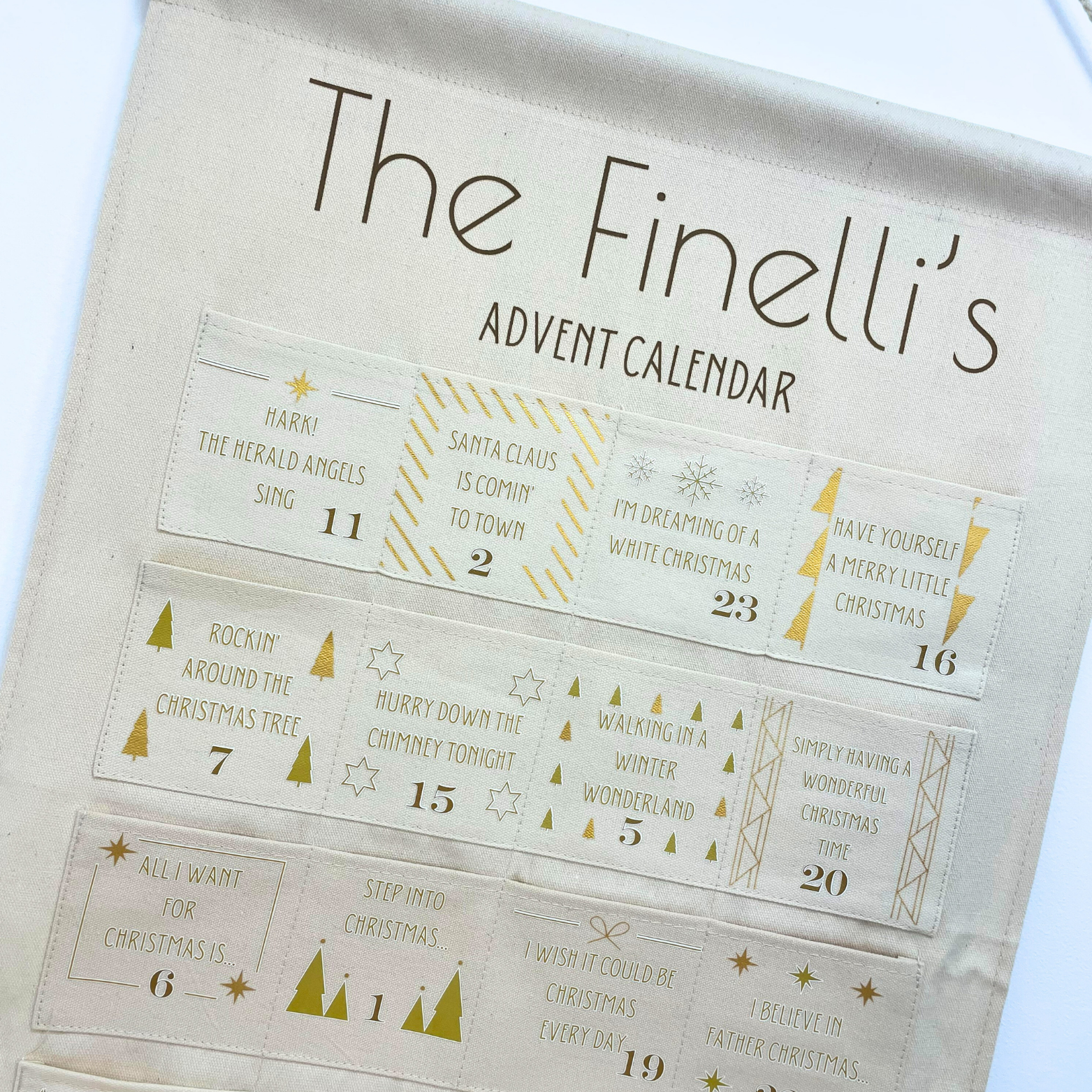 Personalised festive song calendar hanging on wall with 24 numbered pockets